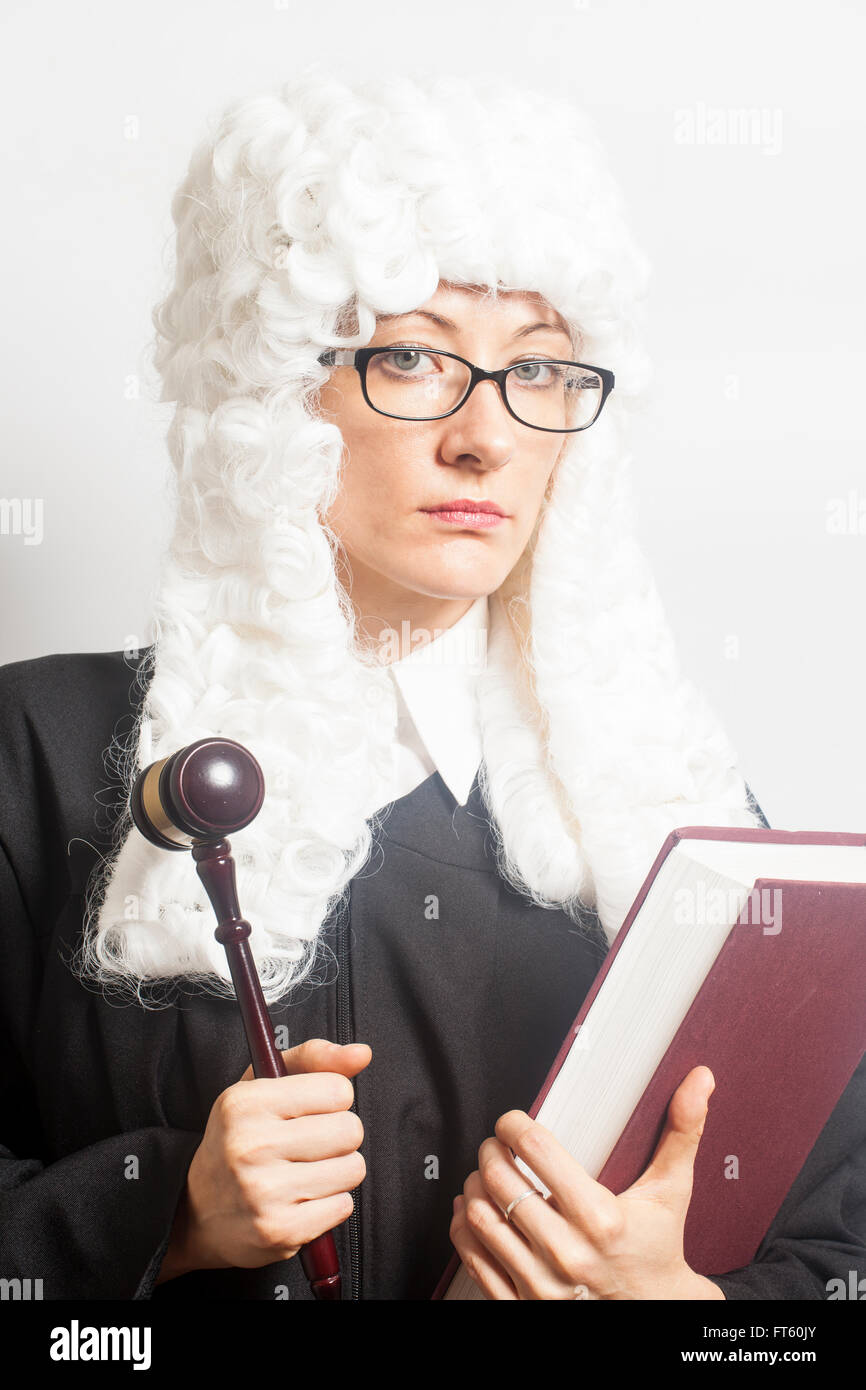 Weibliche Richter tragen einer Perücke und Rücken Mantel mit Brille hält Richterhammer und Buch auf weißen backgriund Stockfoto