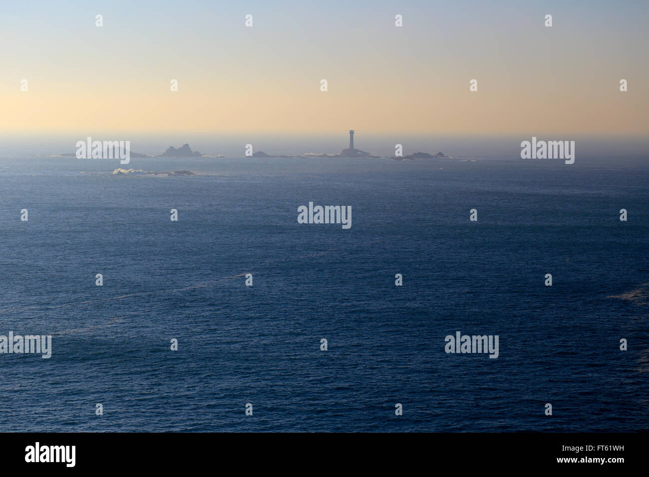 Ein ruhiger See im Abendlicht, die Langschiffe Leuchtturm aus Lands End in Cornwall, England, UK. Stockfoto