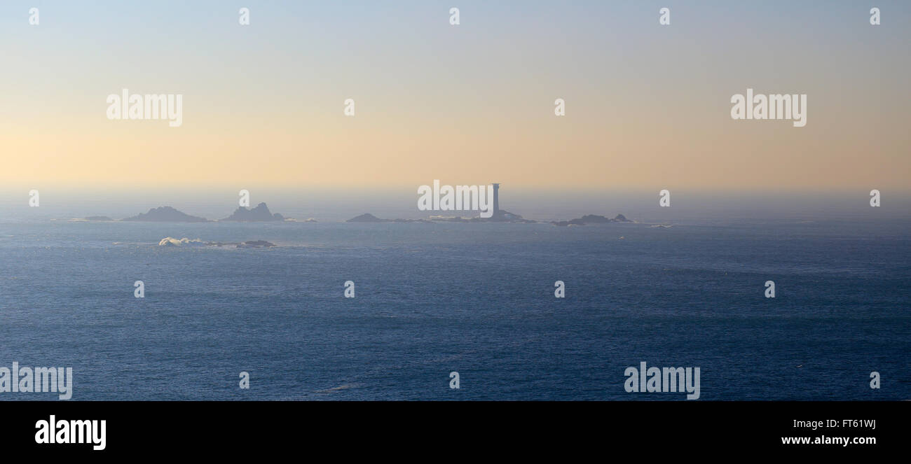 Ein ruhiger See im Abendlicht, die Langschiffe Leuchtturm aus Lands End in Cornwall, England, UK. Stockfoto