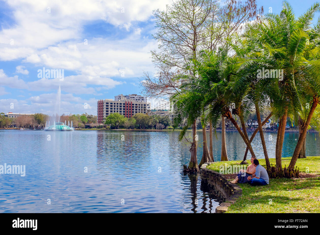 Mann und Frau sitzen am Ufer des Lake Eola, Innenstadt von Orlando, Florida, Amerika. Stockfoto