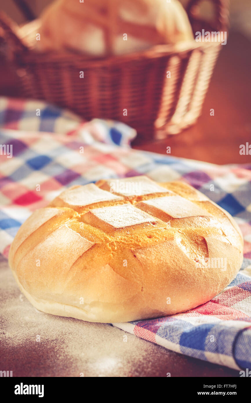 Runder Laib Brot mit Küche Lappen, Mehl und geflochtenen Korb Stockfoto