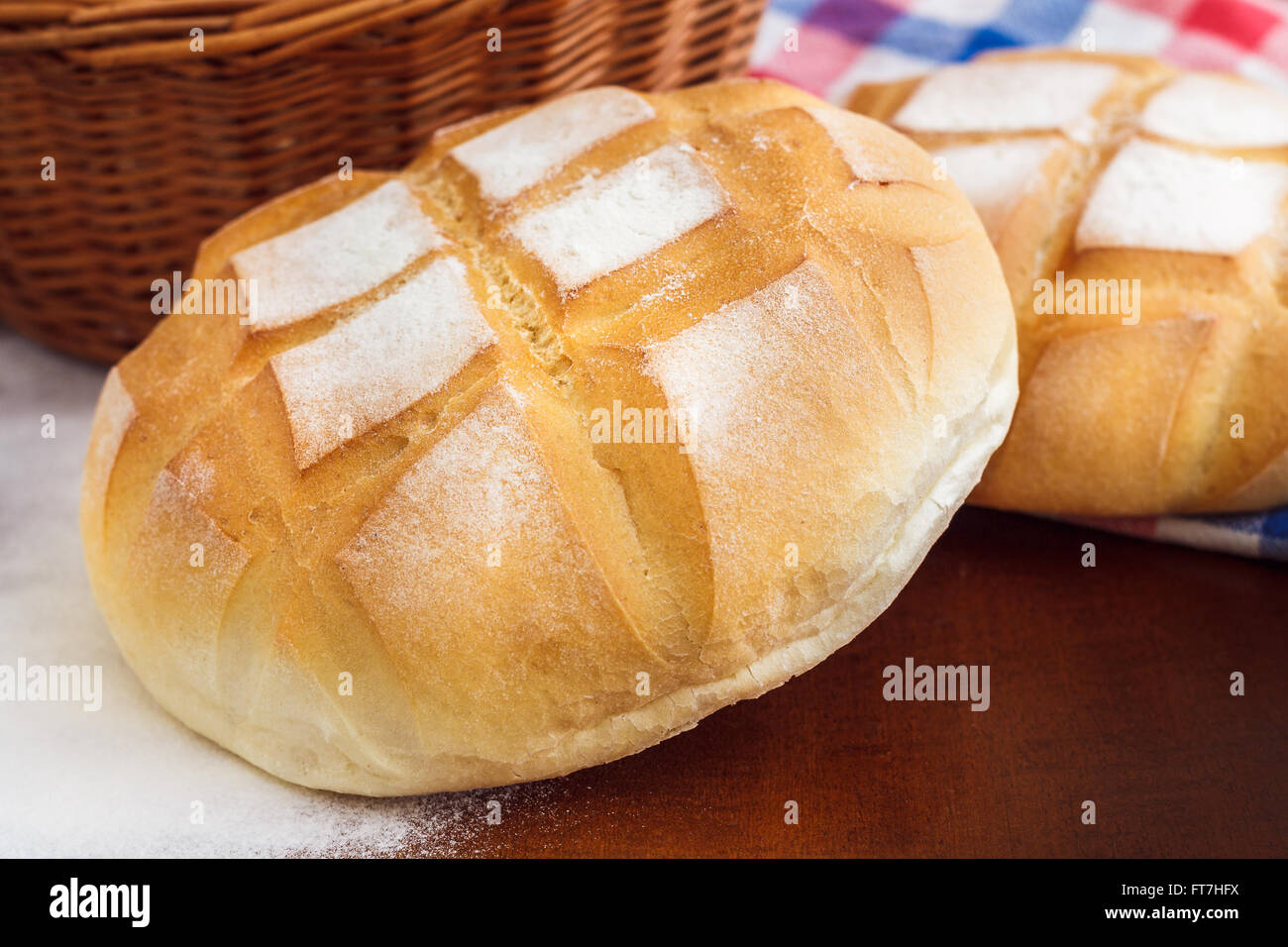 Runder Laib Brot mit Küche Lappen, Mehl und geflochtenen Korb Stockfoto