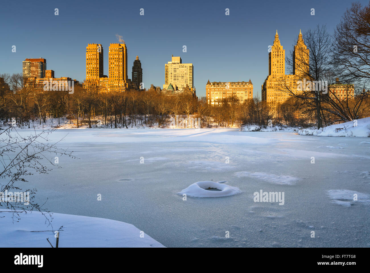 Winter-Sonnenaufgang am zugefrorenen See der Central Park mit Blick auf die Upper West Side von Manhattan Gebäude. New York City Stockfoto