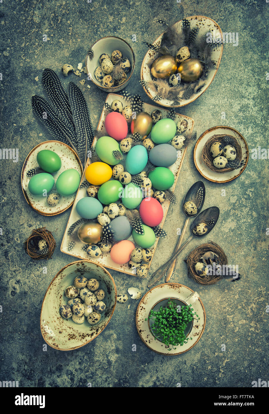 Oster-Deko mit farbigen Eiern und Federn der Vögel. Boho Style Urlaub Hintergrund. Vintage getönten Bild Stockfoto