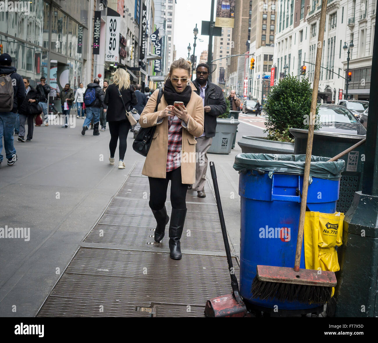 Ein Shopper Texte während des Gehens in Midtown Manhattan in New York auf Freitag, 18. März 2016. (© Richard B. Levine) Stockfoto