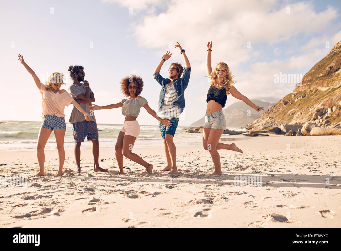 Multi-ethnischen Gruppe von Freunden zusammen am Strand Spaß haben. Glückliche junge Menschen tanzen am Strand. Gruppe von Freunden enjoyi Stockfoto