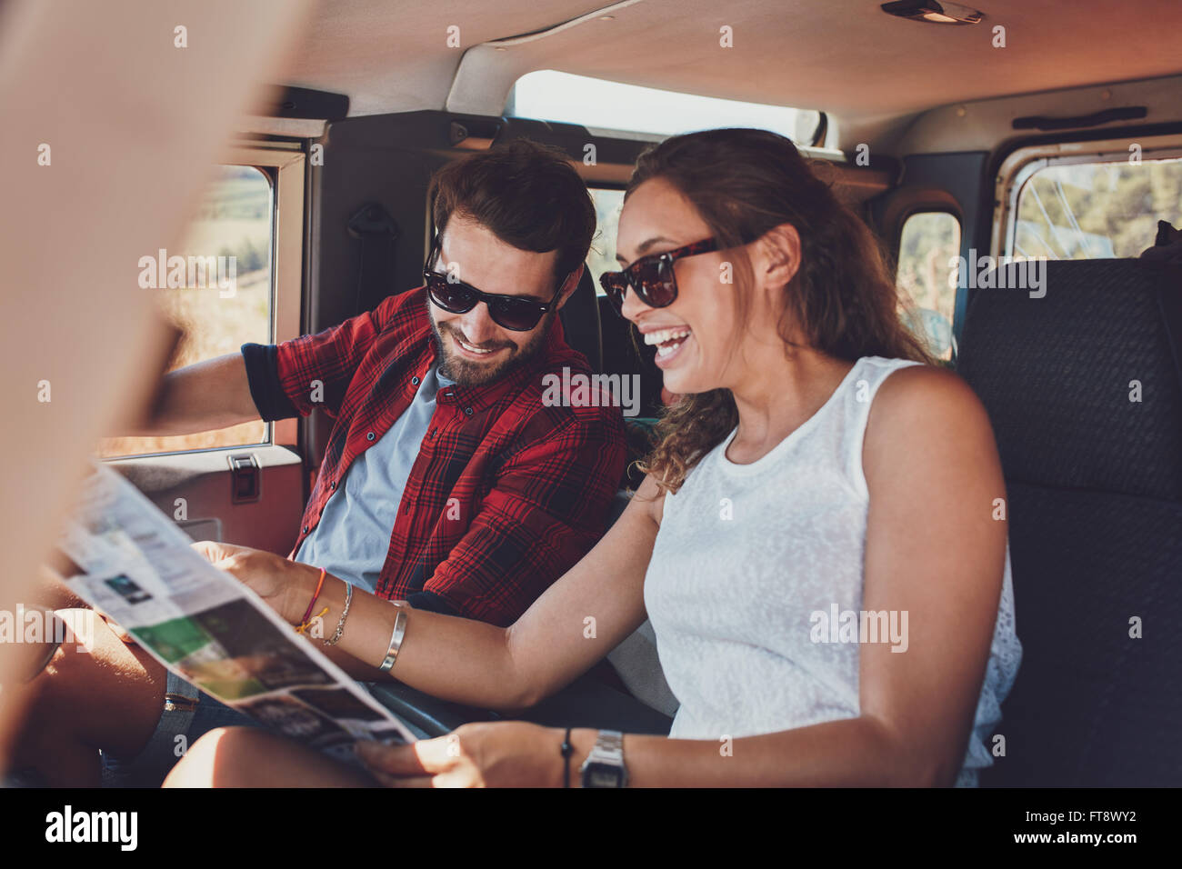 Glückliches junges Paar Planung ihrer Reisen zusammen lesen einer Karte beim Sitzen in ihrem Auto. Lächelnder Mann und Frau mit Karte auf Stockfoto