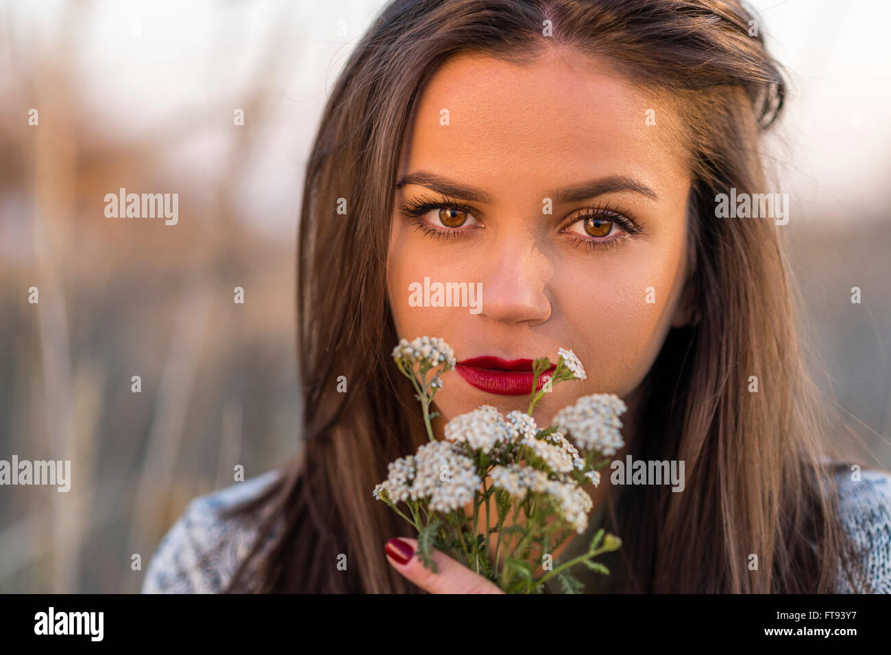 Traurig Herbstlook. Porträt von ein schöne Teenager-Mädchen mit kleinen Blumenstrauß in einem Herbst Feld. Mädchen hat braune Augen und roten Lippen. Stockfoto