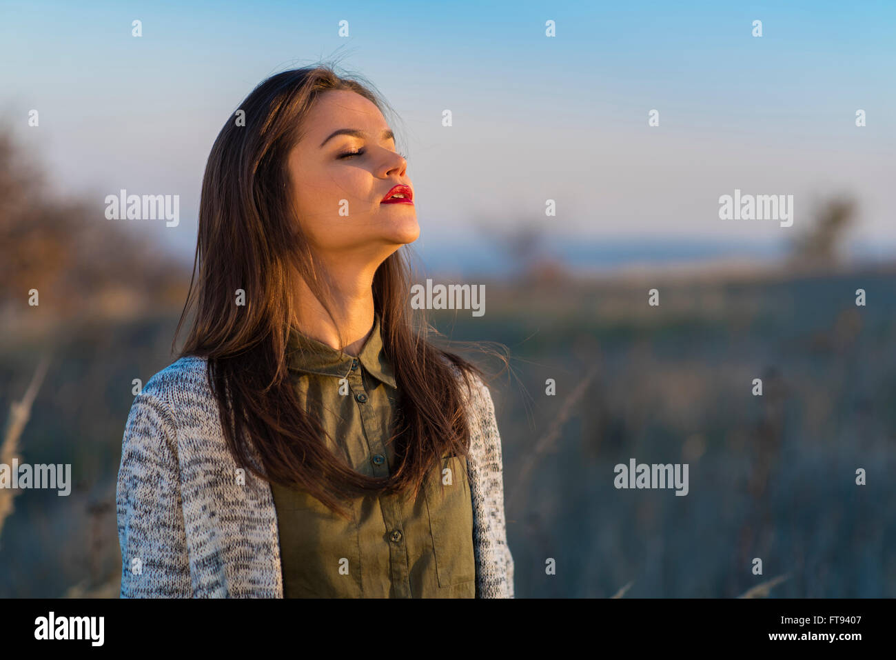Genießen Sonne, vor dem Winter. Eine schöne Teenager-Mädchen in einem Feld bei herbstlichen Sonnenuntergang stehen, genießen die letzten Sonnentage vor dem Winter. Stockfoto