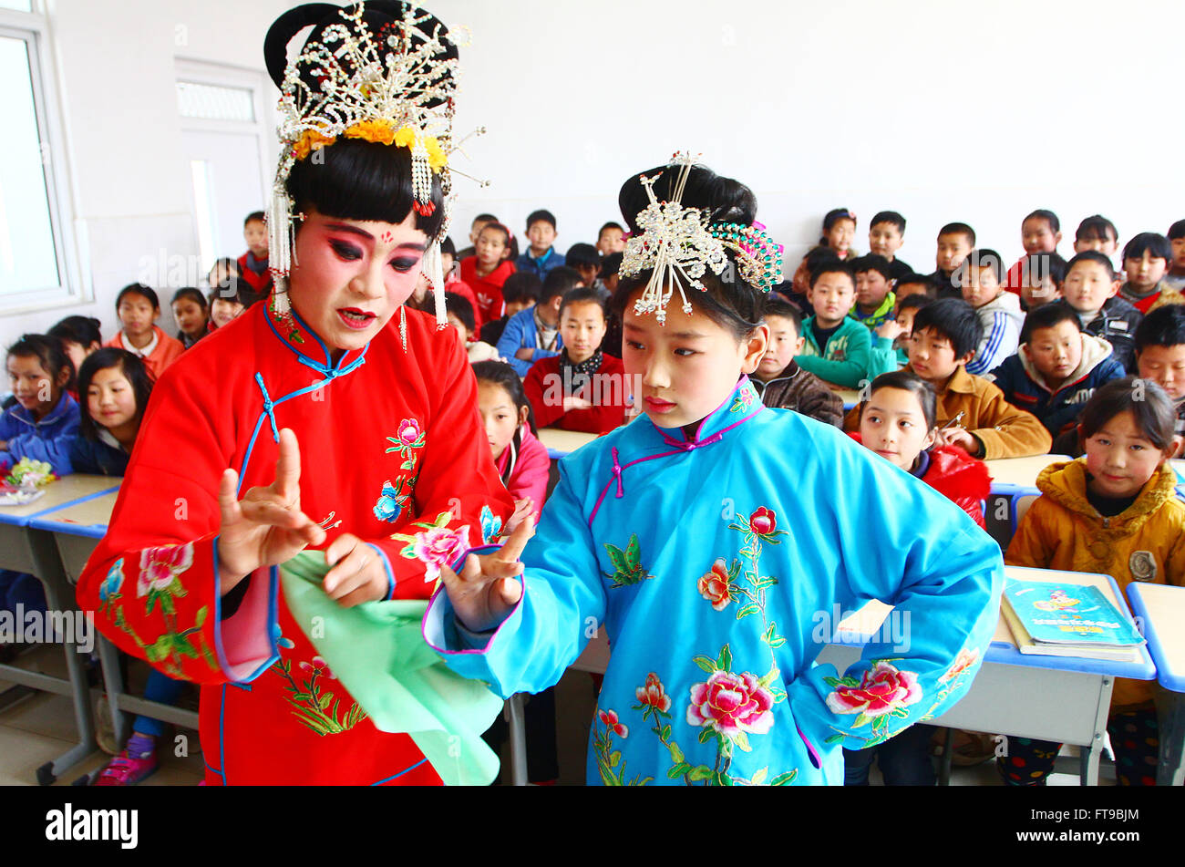 Zaozhuang, China Shandong Provinz. 25. März 2016. -Opera-Darstellerin Shao Hong weist Studenten Zhao Yanyang in Donglu Elementary School in Zaozhuang City in der ostchinesischen Provinz Shandong, 25. März 2016 Gesten. Oper Schauspieler durften Schüler als die Welt-Theater-Tag Ansätze Opern beizubringen. Die Welt-Theater-Tag wurde im Jahr 1961 von des Internationalen Theaterinstituts erschaffen. Es wird jedes Jahr am 27. März von Theater Unternehmen Aournd der Welt gefeiert. Bildnachweis: Zhang Qiang/Xinhua/Alamy Live-Nachrichten Stockfoto