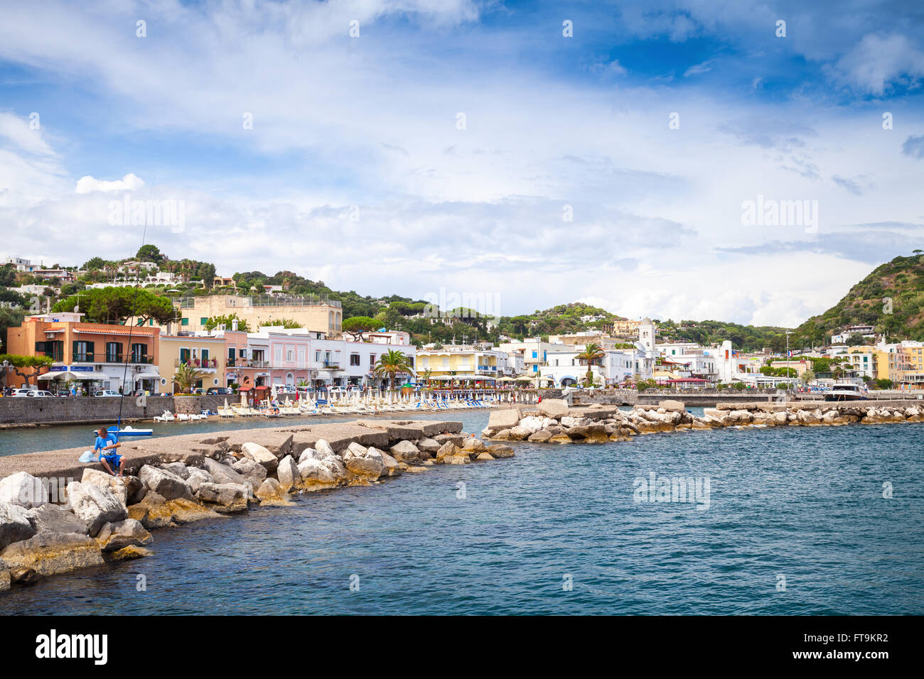 Lacco Ameno, Italien - 11. August 2015: Sommer am Meerblick auf Lacco Ameno, Fischer sitzt auf steinernen Wellenbrecher. Ischia Stockfoto