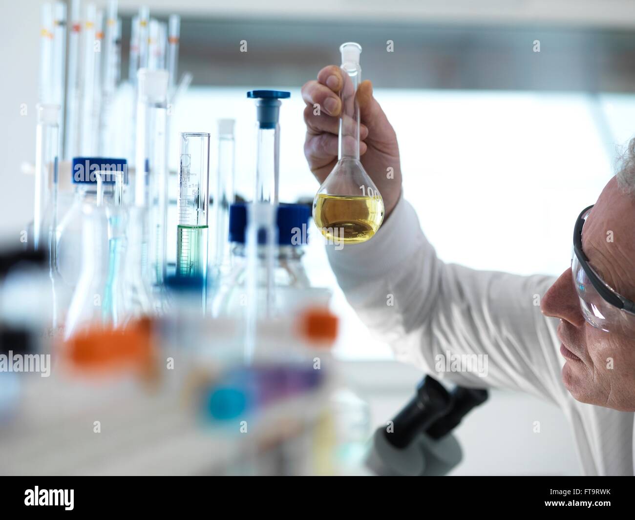 EIGENTUM FREIGEGEBEN. -MODELL VERÖFFENTLICHT. Wissenschaftler halten einer chemischen Lösung besteht in einem Kolben während eines Experimentes in einem Labor. Stockfoto