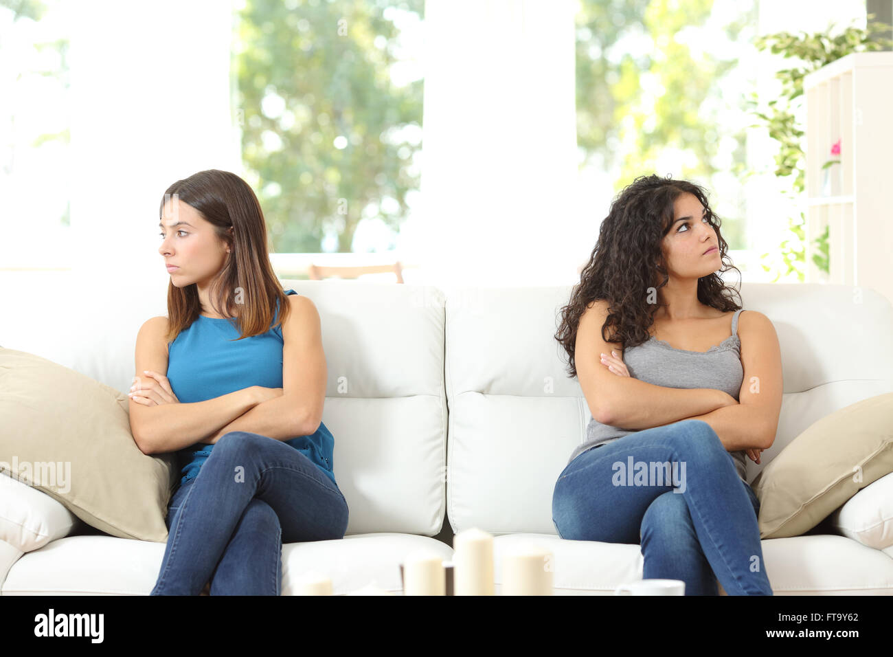 Zwei böse Freunde nach einem Streit auf einer Couch sitzend und mit Blick auf die andere Seite Stockfoto