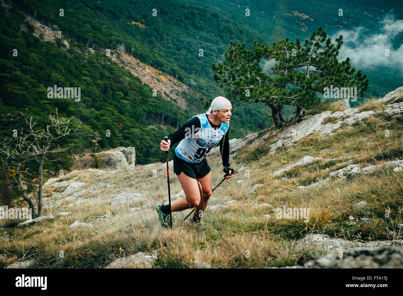 Mann mittleren Alters mit Walking-Stöcken während Bergmarathon bergauf gehen Stockfoto