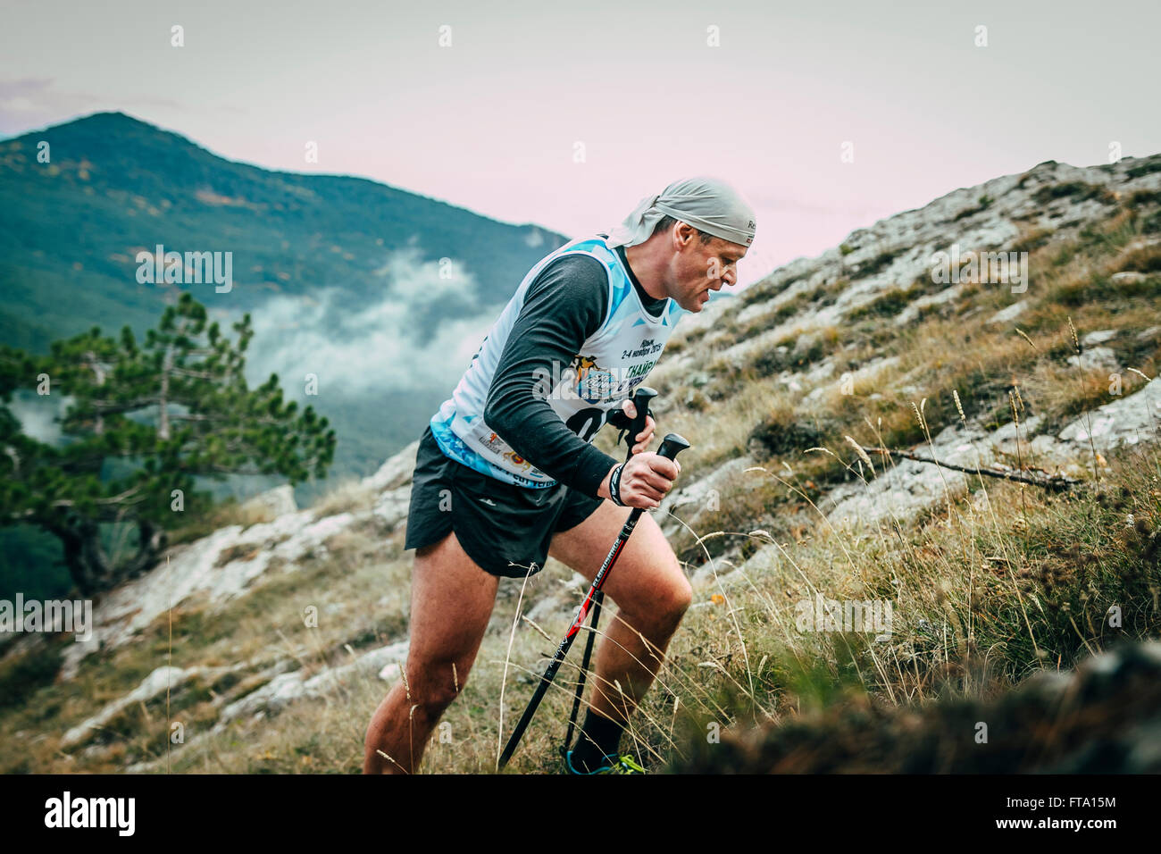 Mann mittleren Alters mit Stöcken ist auf Seite des Berges während Bergmarathon Stockfoto