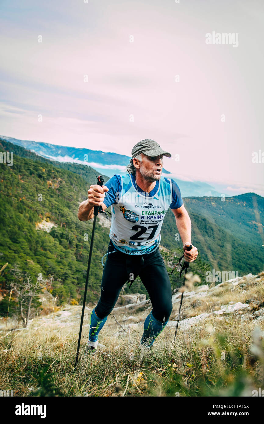 attraktiver Mann mittleren Alters besteigt Berg mit nordic-walking-Stöcke während Bergmarathon Stockfoto
