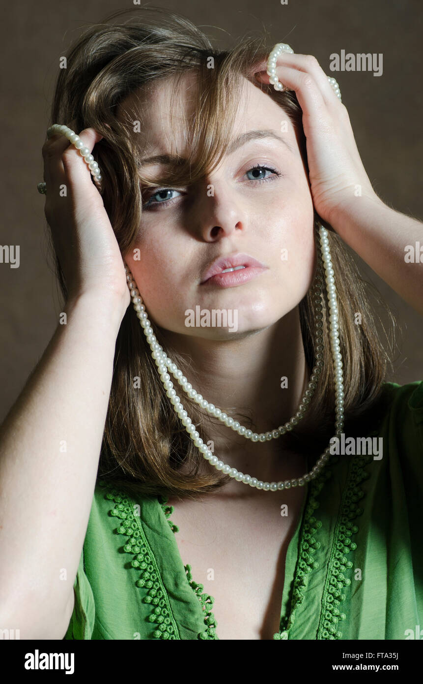 Schöne junge Frau hält eine Perlenkette in der Nähe von ihrem Gesicht Stockfoto