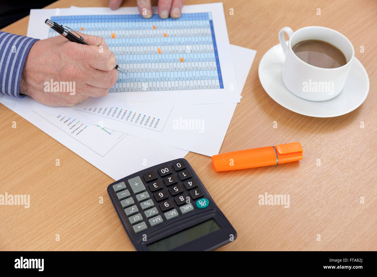 Buchhalter an seinem Schreibtisch Verwendung eines Taschenrechners und finanziellen Bericht prüfen Stockfoto