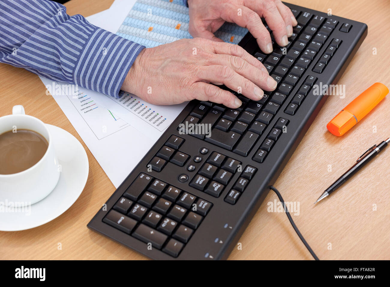 Buchhalter an seinem Schreibtisch mit einem Computer-Tastatur einen Finanzbericht zu überprüfen Stockfoto