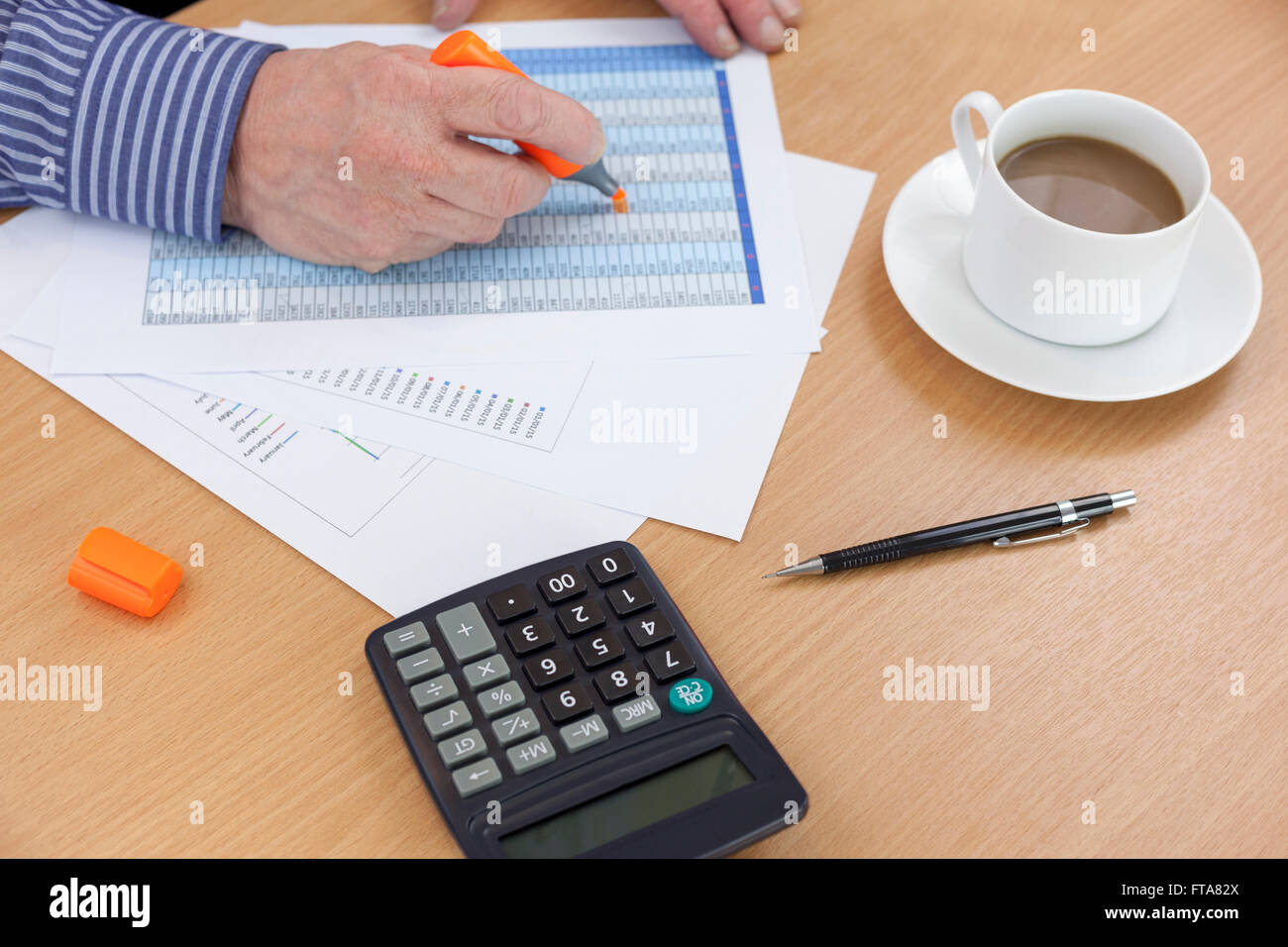Buchhalter beschäftigt an seinem Schreibtisch mit einer orange Textmarker auf einem Arbeitsblatt Stockfoto