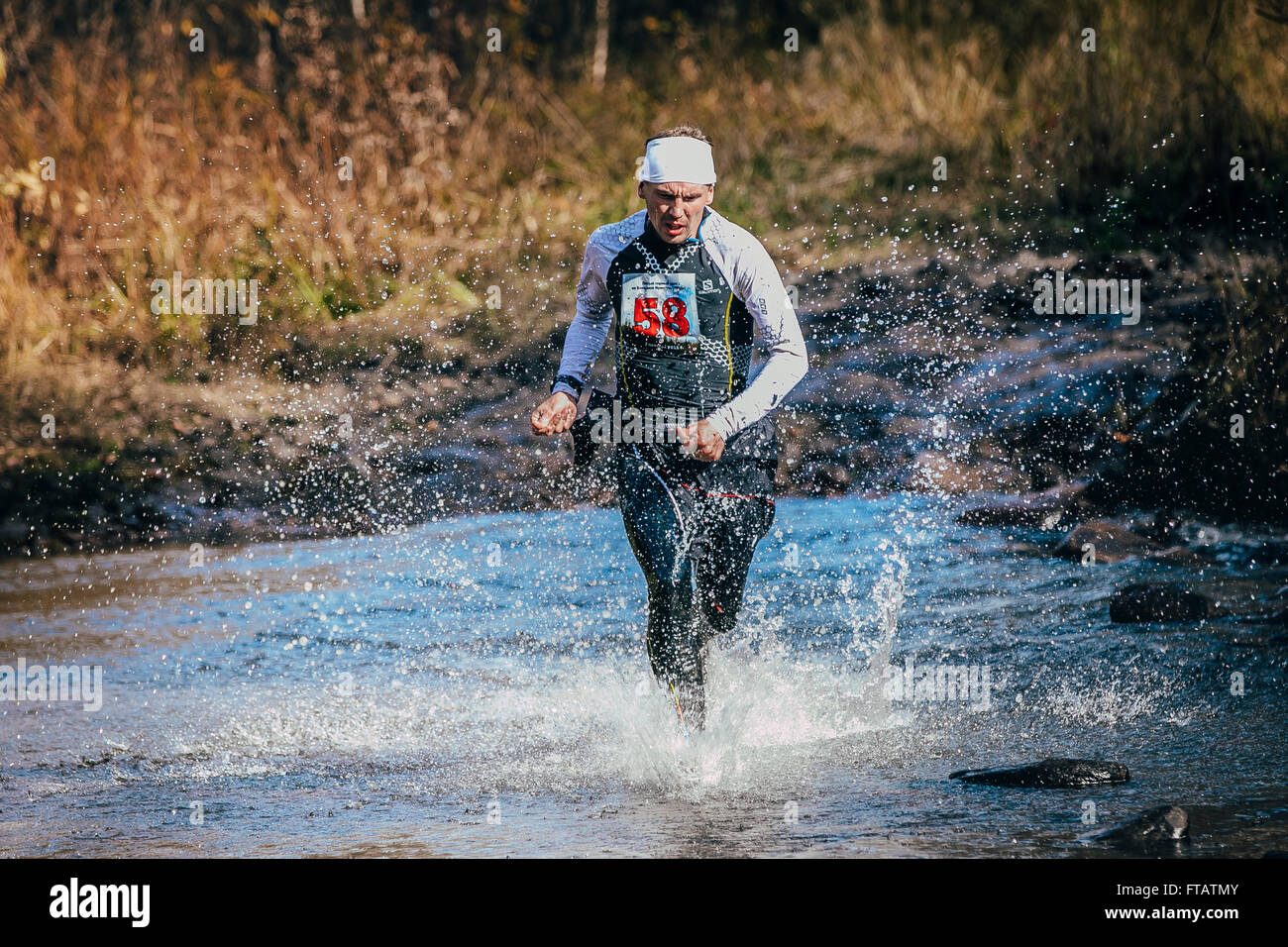Belorezk, Russland - 26. September 2015: Läufer im mittleren Alter Mann Kreuzung Fluß, und um ihn herum Wasser spritzt beim Marathon Stockfoto