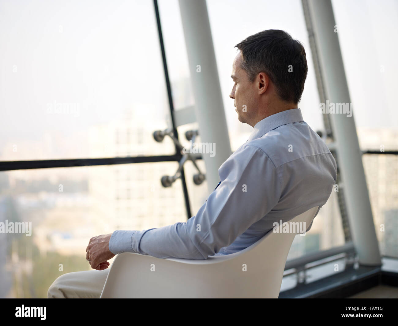 Geschäftsmann, sitzen durch das Fenster denken Stockfoto