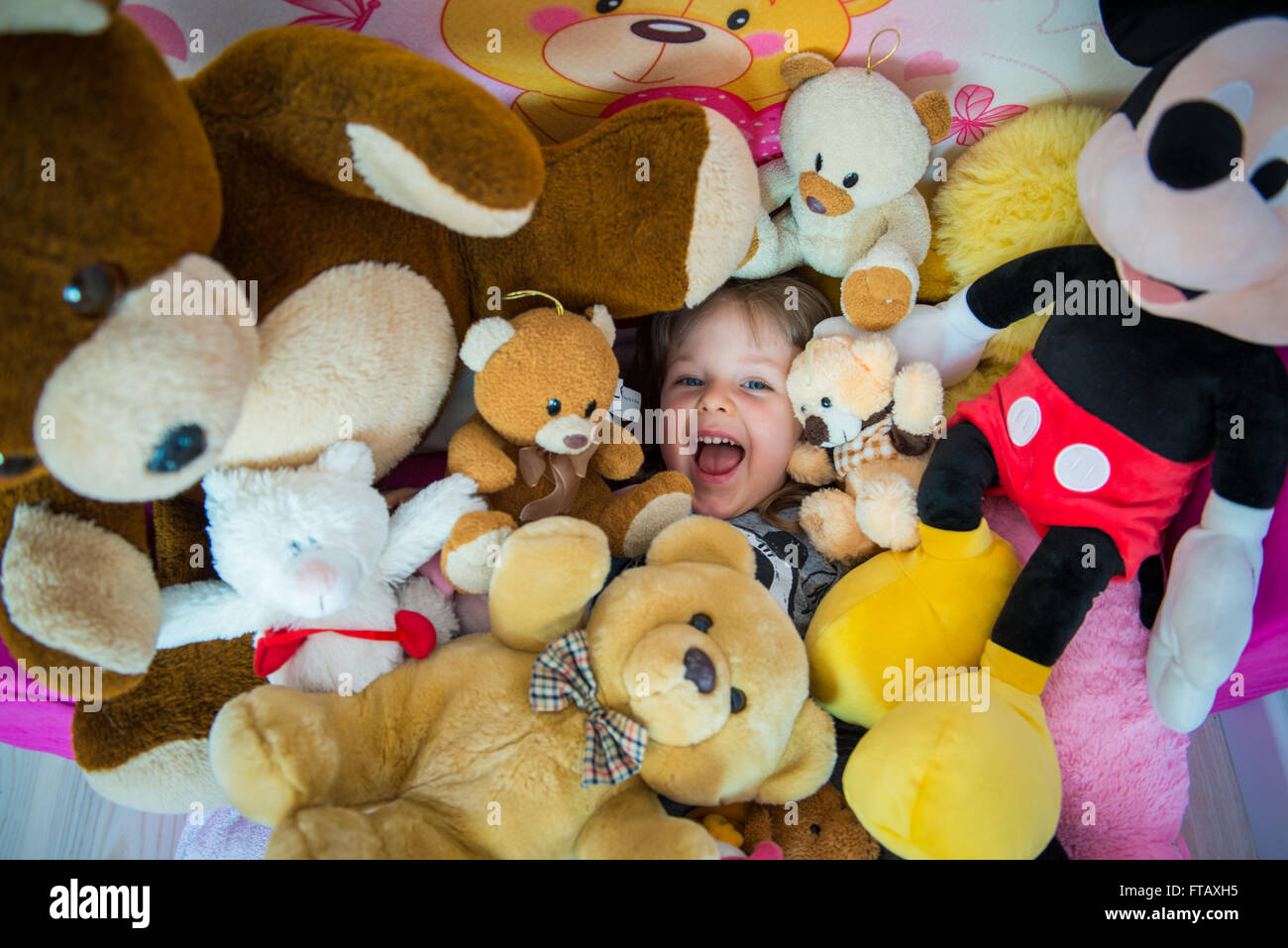 drei Jahre altes Mädchen voller Plüschtiere Stockfoto