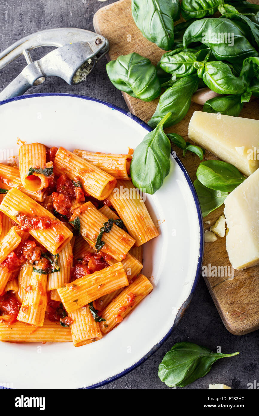 Nudeln. Italienische und mediterrane Küche. Pasta Rigatoni mit Tomaten-Sauce Basilikum Blätter Knoblauch und Parmesan-Käse. Ein altes Haus Stockfoto
