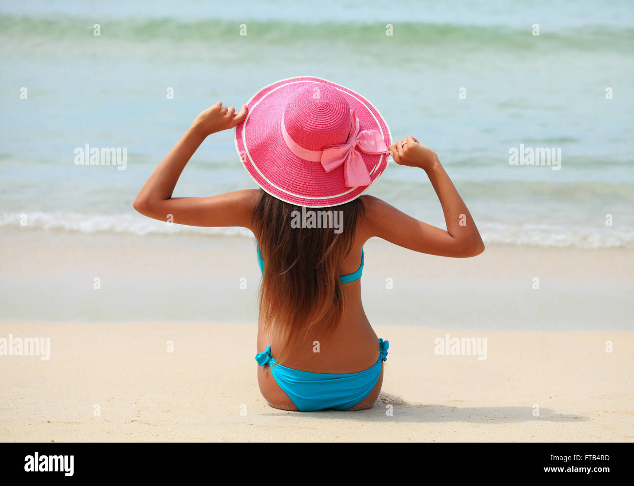 Frau in großen Hut sitzt am Strand am Meer Stockfoto