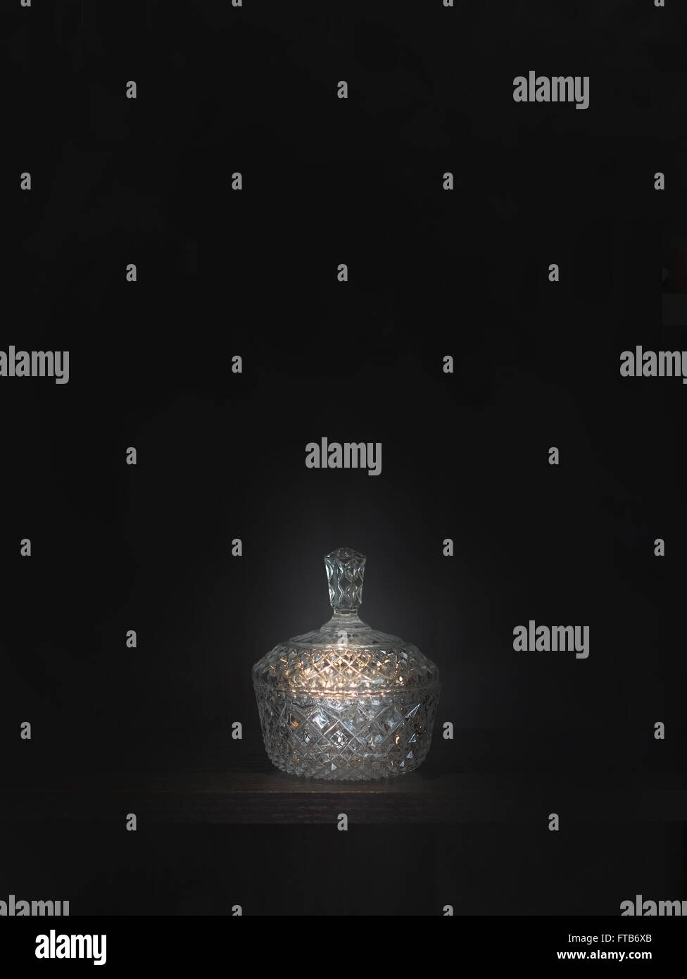 Kristall Schale mit Deckel vor einem dunklen Hintergrund, hell-dunkel-Stil. Stockfoto