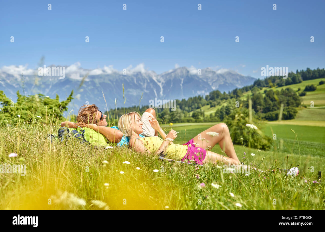 Mann und Frau liegt in einer Blumenwiese mit Blick auf die North Kette, Patsch, Innsbruck, Österreich Stockfoto