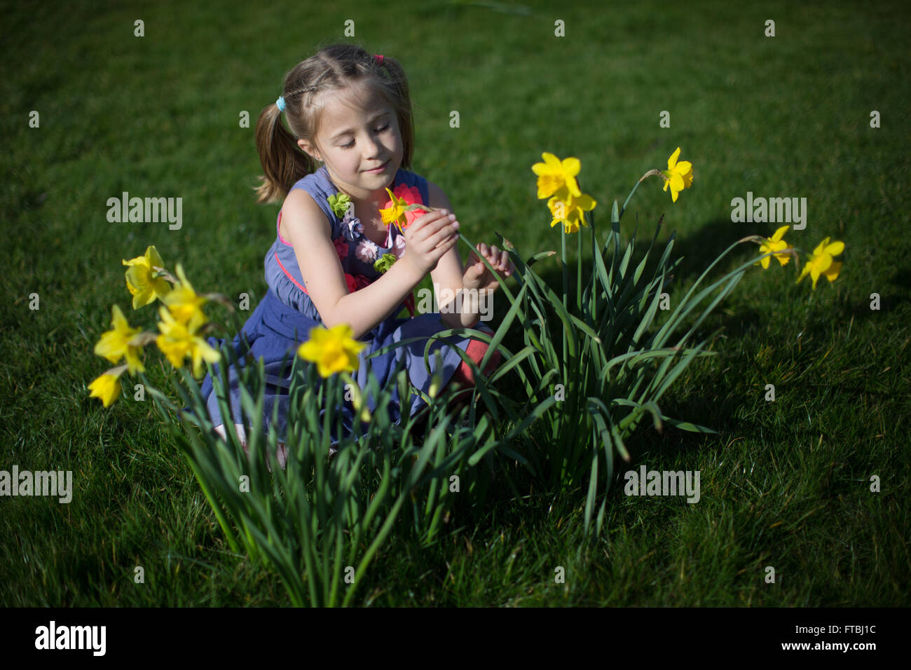 Ein junges Mädchen posiert mit Narzissen in Greenwich, England, UK Stockfoto