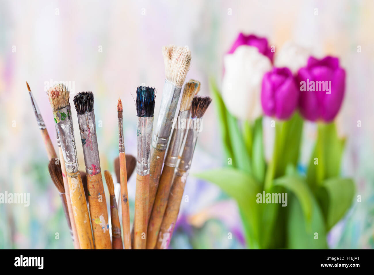 Künstlerische Malerpinsel, Blumenstrauß aus Tulpen und Malerei auf Hintergrund Stockfoto