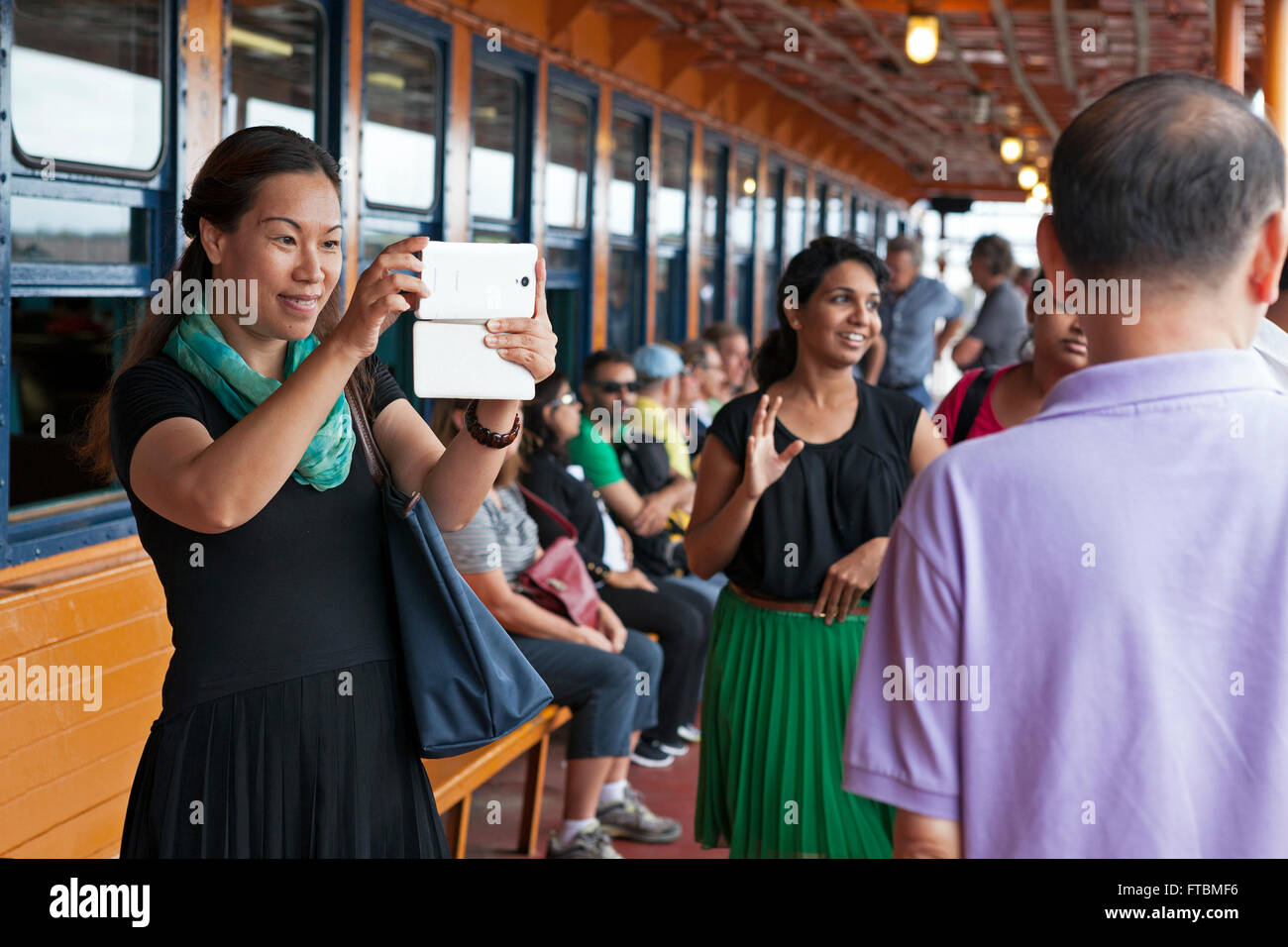 Menschen aus der ganzen Welt fotografieren einander auf der Staten Island Ferry in New York City. Stockfoto