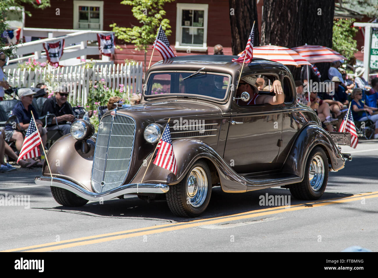 Ein angepasster brauner Hot Rod drückt die Paradestrecke wie die Fahrer-Wellen zur Masse während der Mohawk Valley Parade. Stockfoto