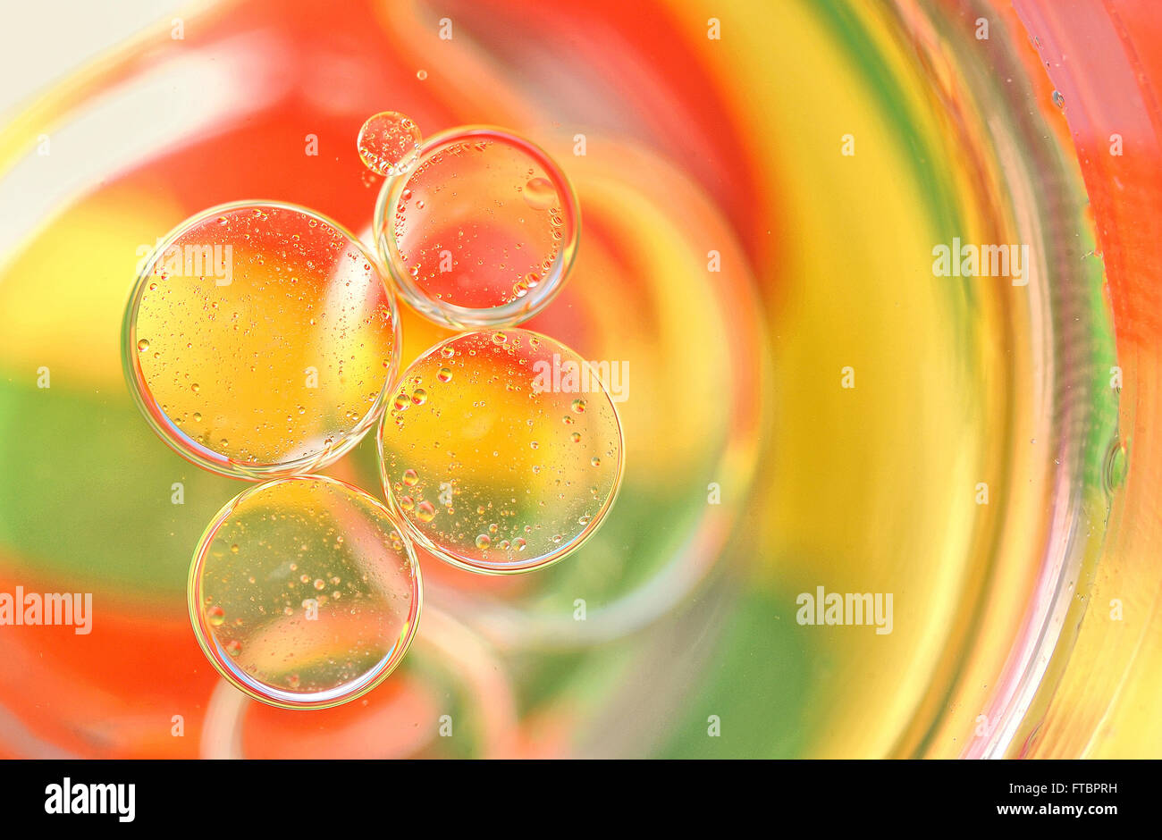 Öltropfen auf einer Wasseroberfläche mit Farben im Hintergrund Stockfoto