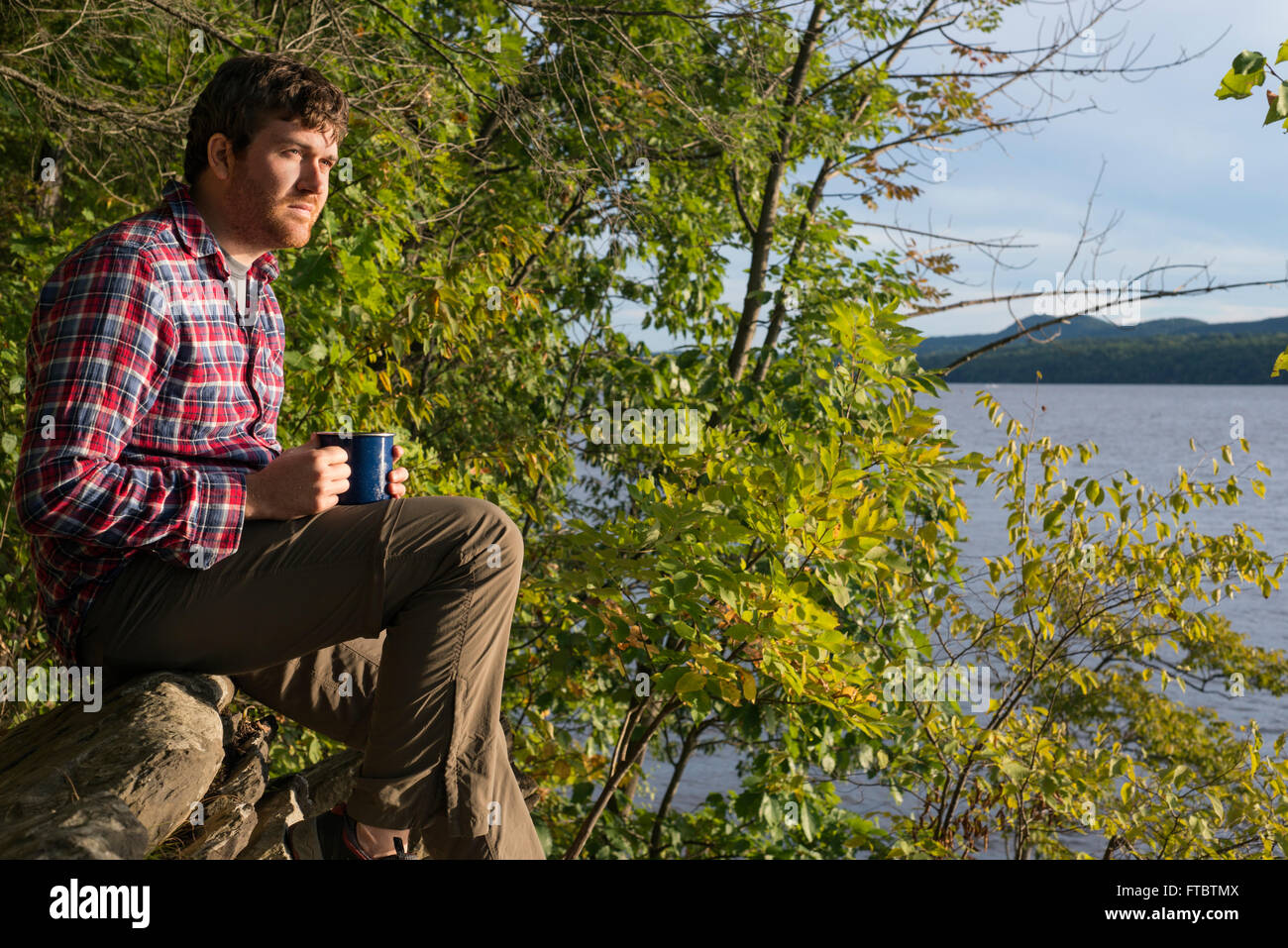 Ein Mann trinkt Kaffee und Blick auf den Hudson River von Camp Morris Norrie, New York Stockfoto