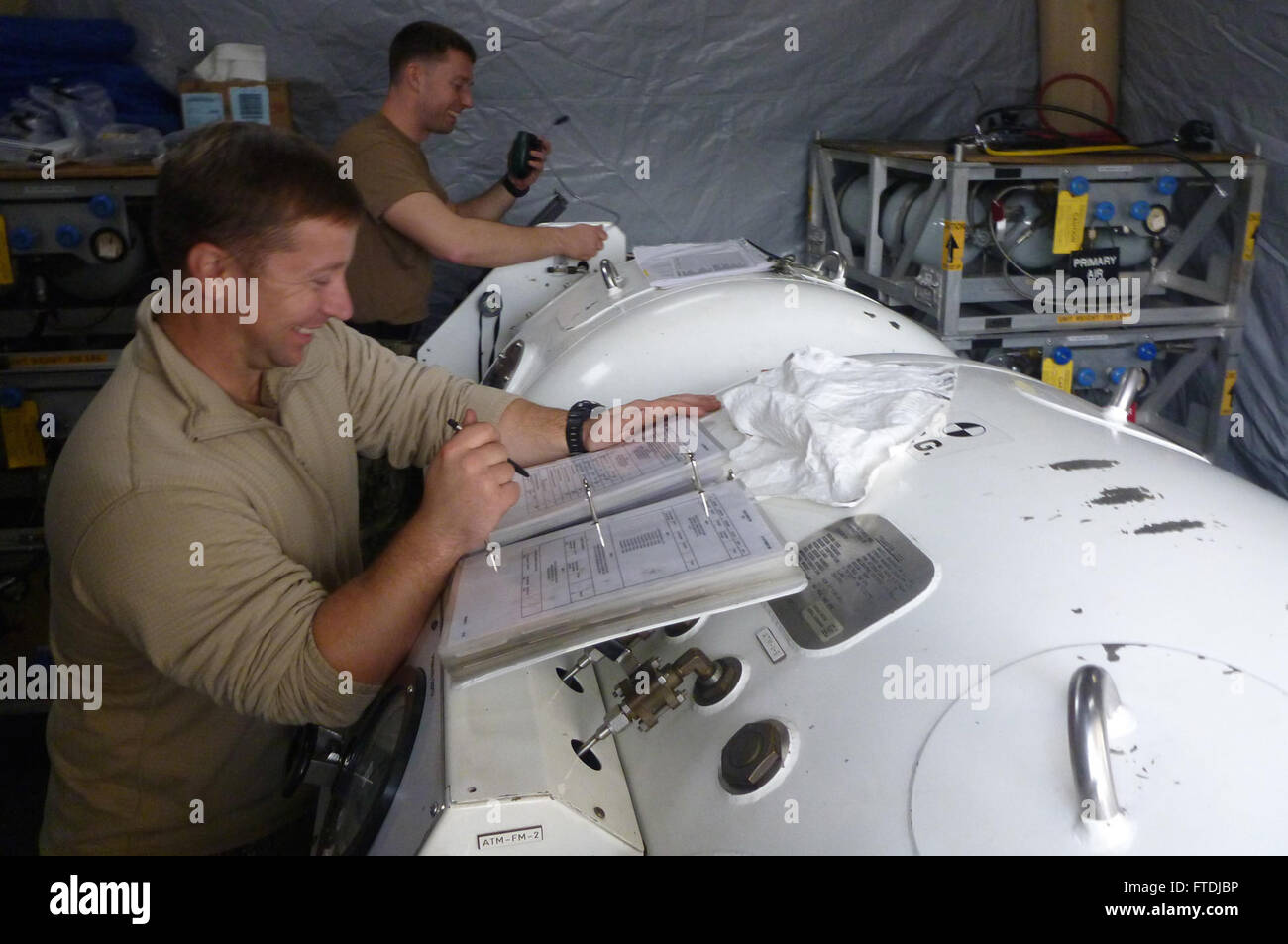 Ein Foto von Tauchern der US Navy, die während eines militärischen Einsatzes mit kroatischen EOD-Tauchern operative Kontrollen an einer Rekompressionskammer durchführen. Das Bild zeigt die militärische Zusammenarbeit und die technische Kompetenz bei Unterwassereinsätzen. Stockfoto
