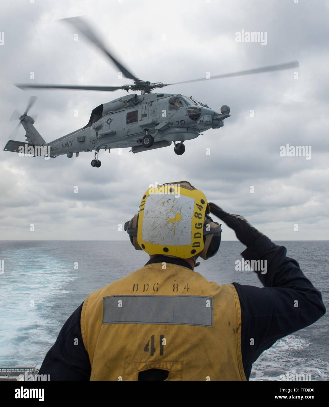 Ein Foto der US Navy vom 3. Dezember 2015 an Bord der USS Bulkeley (DDG 84), auf dem Boatswain's Mate 3rd Class D. Kostenbauder einen MH-60R Sea Hawk Hubschrauber nach dem Betanken während des Fluges begrüßt. Das Bild zeigt die Marineoperationen im Mittelmeer. Stockfoto