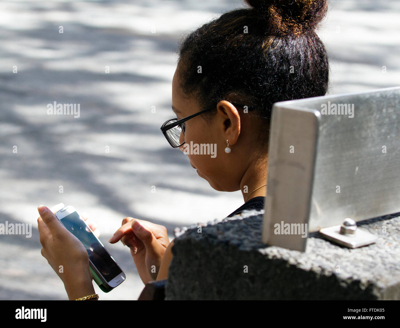 Frau setzte sich mit Handy im freien Stockfoto