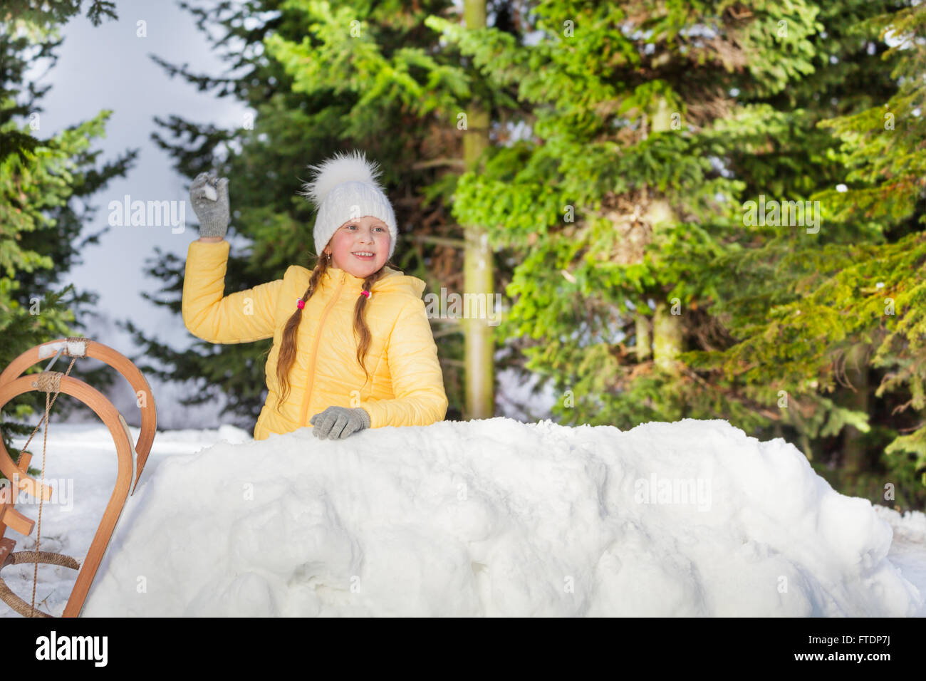 Glückliches Mädchen werfen Schneeball aus dem Schnee-Turm Stockfoto