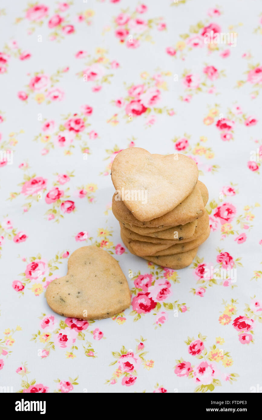 Ein Stapel von Herzen geformt Cookies auf einem floralen Hintergrund. Stockfoto