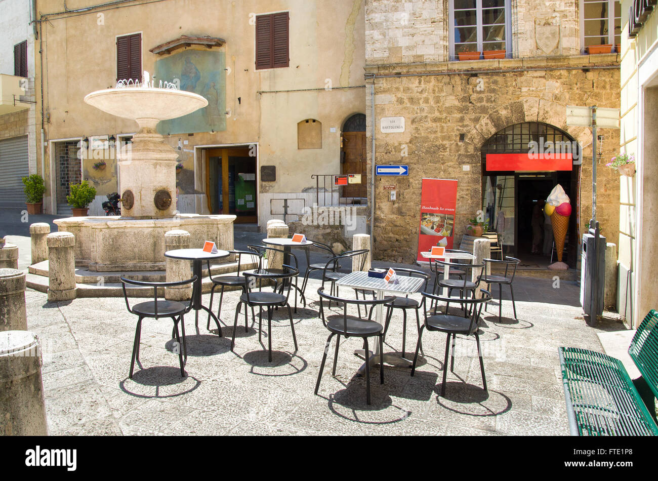 Leere Tabellen treffen zeigen kleine quadratische Brunnen Bar Gelateria in Asciano - Siena Toskana Italien Stockfoto