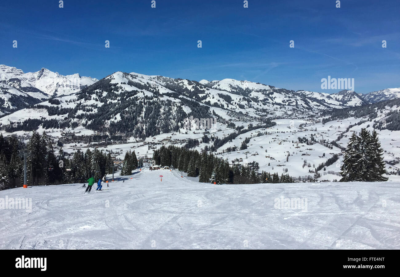 Skipiste in der Gstaad Wintersportgebiet. Im Hintergrund Berge und das Dorf Schönried. Gstaad, Schweiz. Stockfoto