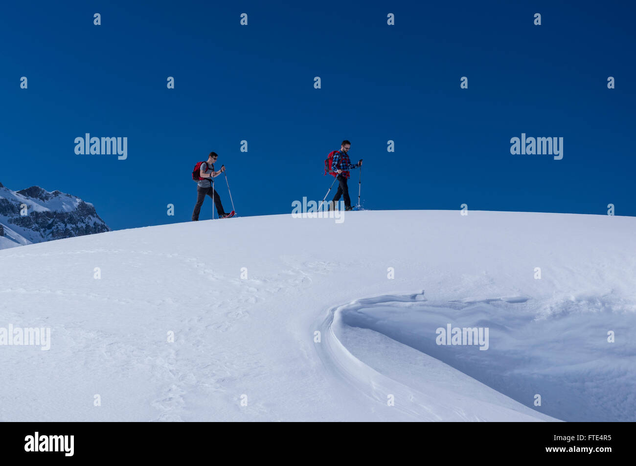 Zwei männliche Schneeschuhwanderer an einem sonnigen Wintertag in den Schweizer Alpen wandern. Melchsee-Frutt, Kanton Obwalden, Schweiz. Stockfoto