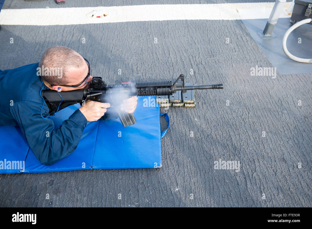 Dieses Bild zeigt den leitenden Sonar-Techniker Brian Morgan, der während einer Übung zur Kleinwaffenqualifikation an Bord der USS Stout (DDG 55), einem Lenkraketenzerstörer der Arleigh-Burke-Klasse, im Mittelmeer im Rahmen der Sicherheitsbemühungen der US-Navy eingesetzt wird, ein M4-Karabingewehr abfeuert. Stockfoto