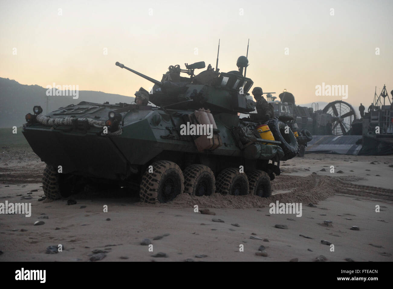 Dieses Bild zeigt die US-Marines an Bord der USS Bataan (LHD 5), die sich darauf vorbereiten, während einer Militäroperation ein leichtes gepanzertes Fahrzeug auf ein Luftkissen des Landungsbootes zu laden. Die USS Bataan ist Teil der amphibischen Angriffsflotte der US Navy und unterstützt maritime Sicherheitseinsätze. Stockfoto