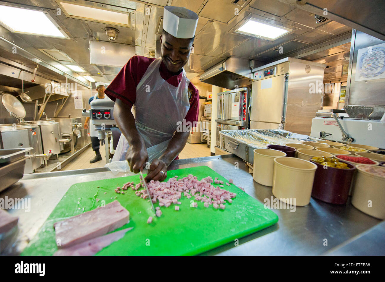 Der kulinarische Spezialist Seaman Isaiah Harris wird während seines Hafenbesuchs in Marseille im Jahr 2014 in der Galeere der USS Arleigh Burke (DDG 51) bei der Zubereitung von Speisen beobachtet. Das Schiff wurde zur Unterstützung der Zusammenarbeit im Bereich Seeverkehrssicherheit und Theatersicherheit im Gebiet der 6. US-Flotte eingesetzt. Stockfoto
