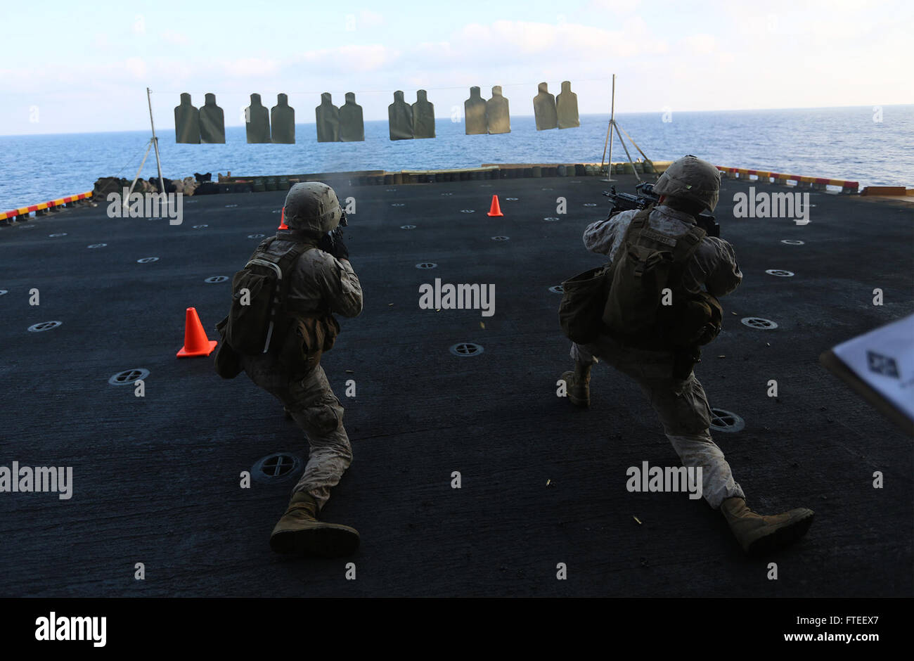 Dieses Bild zeigt zwei US-Marine-Schützen der 22. Marine-Expeditionstruppe, die während eines Feuerwehren an Bord der USS Bataan im Jahr 2014 Ziele angreifen, um Kampfbereitschaft und Training zu demonstrieren. Stockfoto
