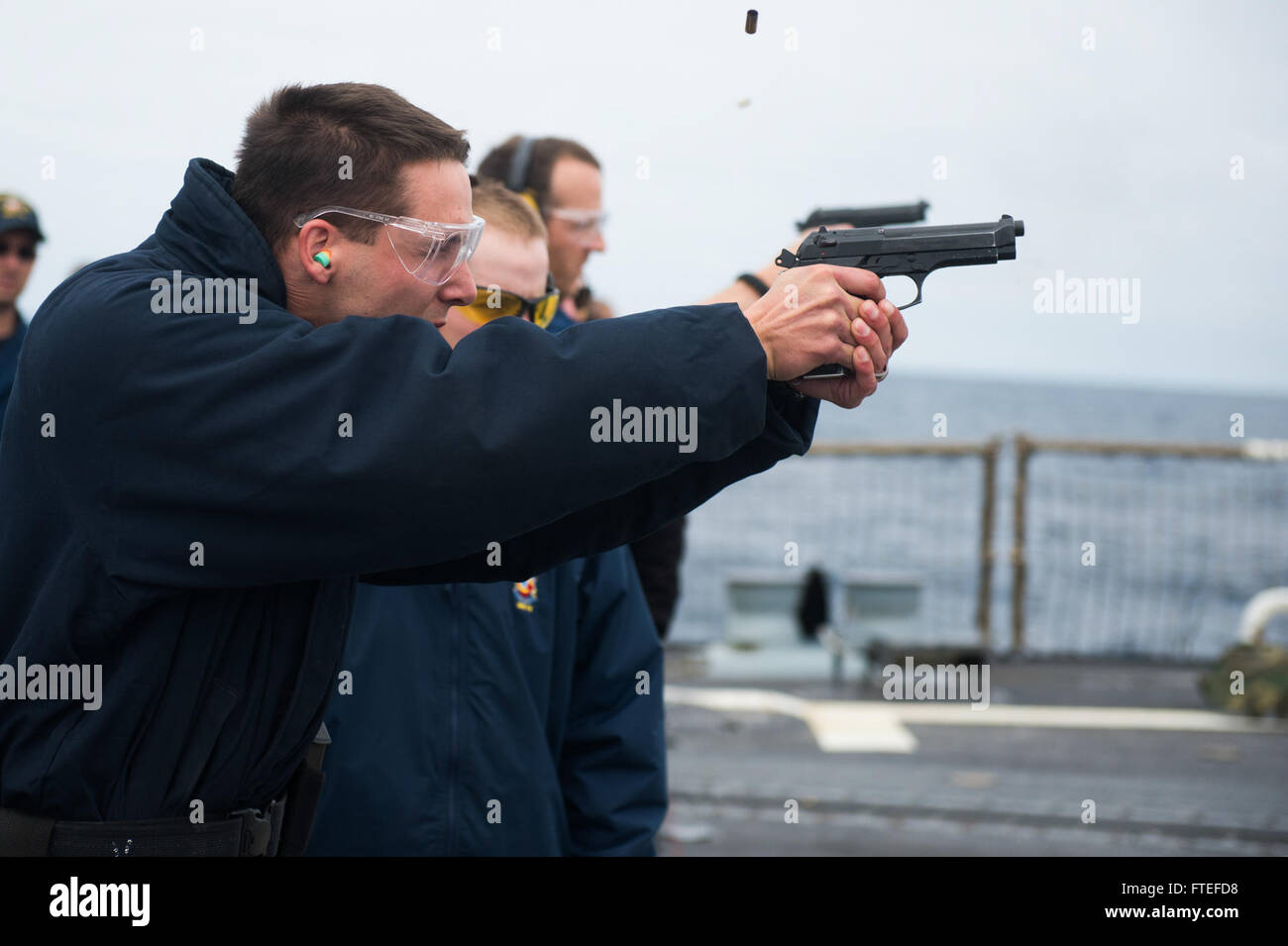 140711-N-YO152-132-Atlantik (11. Juli 2014) - Navy Ratgeber 1. Klasse (FMF) Douglas Edmonston feuert eine 9 mm Pistole Dienst während einer Pistole schießen auf dem Flugdeck an Bord geführte Flugkörper Zerstörer USS Oscar Austin (DDG-79). Oscar Austin, in Norfolk, Virginia, Gridley führt Marineoperationen mit Partnern und Verbündeten in den USA 6. Flotte Einsatzgebiet um Sicherheit und Stabilität in Europa voranzubringen. (Foto: U.S. Navy Mass Communication Specialist 3. Klasse DJ Revell/freigegeben)  Nehmen Sie das Gespräch auf Twitter (https://twitter.com/naveur navaf) folgen Sie uns auf Facebook (https:/ Stockfoto